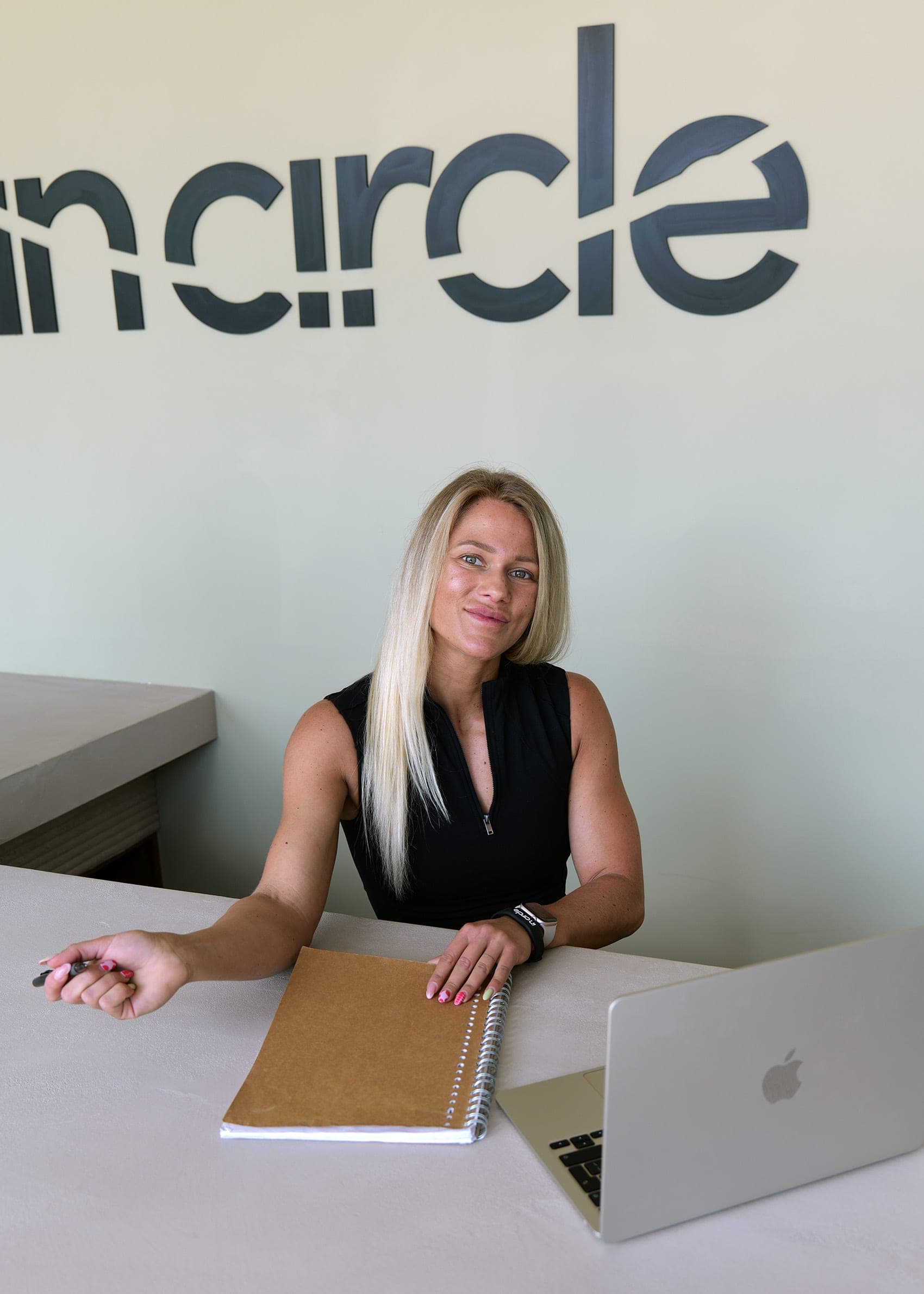 Jill van InCircle aan tafel met laptop en notitieboek, met het InCircle-logo op de muur